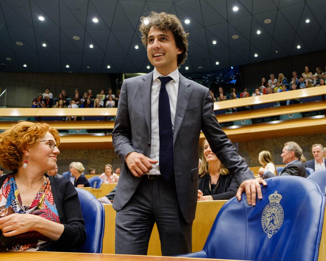 Jesse Klaver staat met een glimlach bij zijn stoel in de Tweede Kamer