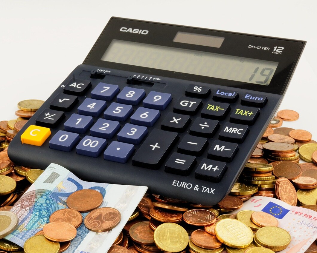 Een rekenmachine ligt op muntgeld en biljetten